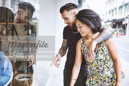 Multi ethnic hipster couple looking and pointing at shop window, Shanghai French Concession, Shanghai, China