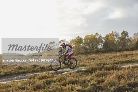 Male mountain biker biking down moorland track