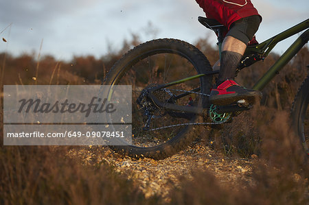 Male mountain biker's wheel skidding on moorland gravel