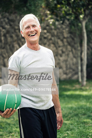 Portrait of man holding basketball looking at camera smiling