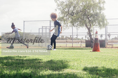 Schoolgirls doing dribbling soccer ball practice on school sports field