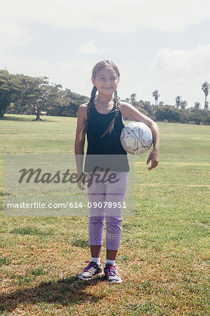 Portrait of schoolgirl holding soccer ball on school sports field