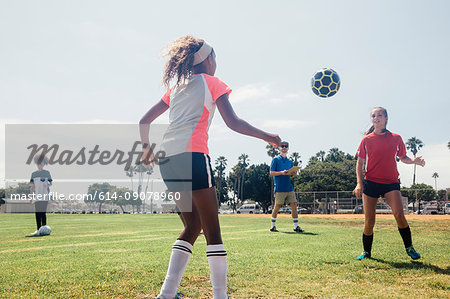 Schoolgirls kicking ball to each other on school sports field