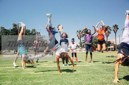 Schoolgirl soccer team doing cartwheel celebration on school sports field