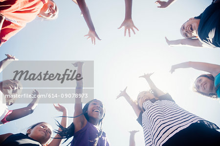 Low angle view of schoolgirl soccer team in circle with arms raised