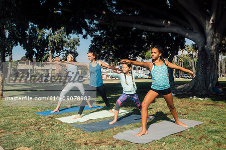 Schoolgirls practicing yoga warrior two pose on school sports field