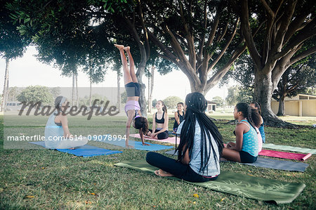 Schoolgirls practicing yoga handstand on school sports field