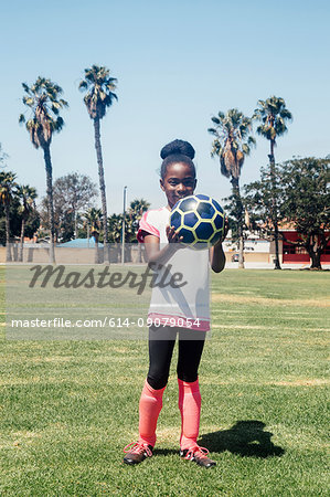 Portrait of schoolgirl soccer player holding soccer ball on school sports field