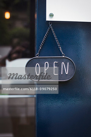 Close up of open sign on glass door to a bakery.