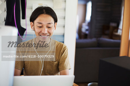 Smiling man sitting indoors at desk, wearing headphones.