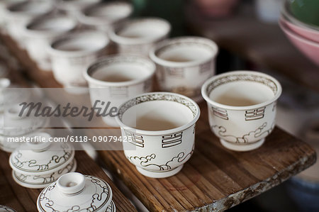 High angle close up of white cups and lids in a Japanese porcelain workshop.
