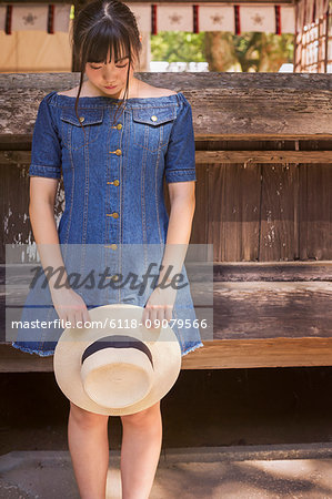 Young woman wearing blue dress and holding hat at Shinto Sakurai Shrine, Fukuoka, Japan.