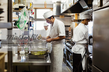 Two chefs working in the kitchen of a Japanese sushi restaurant.