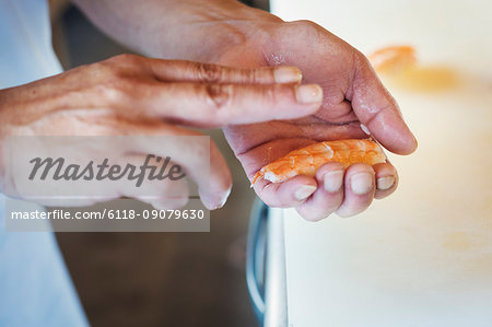 Close up of chef holding a piece of crab, making sushi.