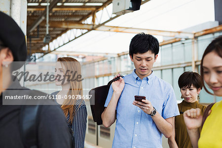 Small group of people standing on the platform of a subway station, Tokyo commuters.