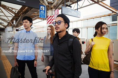 Small group of people standing on the platform of a subway station, Tokyo commuters.