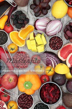 Super food health promoting food concept with fruit, vegetables, pulses and grains high in antioxidants, anthocyanins and vitamins on rustic wood background.