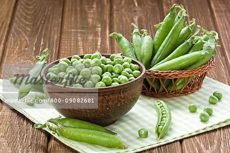 Green peas in ceramic bowl on wooden background