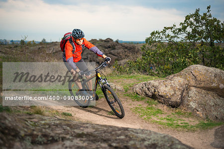 Cyclist in Red Riding the Bike on the Autumn Rocky Trail. Extreme Sport and Enduro Biking Concept.