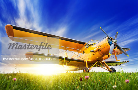 historic biplane on a meadow against a sunset