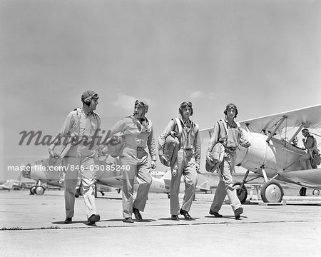 1940S FOUR U.S. NAVY PILOTS WALKING TOGETHER ON TARMAC RETURNING FROM AIR MANEUVERS AT THE PHILADELPHIA NAVY YARD PA USA