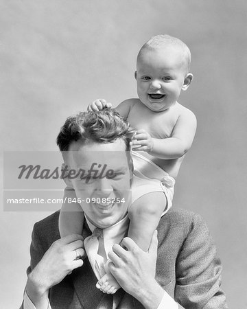 1930s LAUGHING FATHER CARRYING BABY SON ON HIS SHOULDERS AS KID PULLS DAD'S HAIR