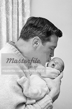 1960s FATHER HOLDING AND KISSING HIS INFANT BABY SON