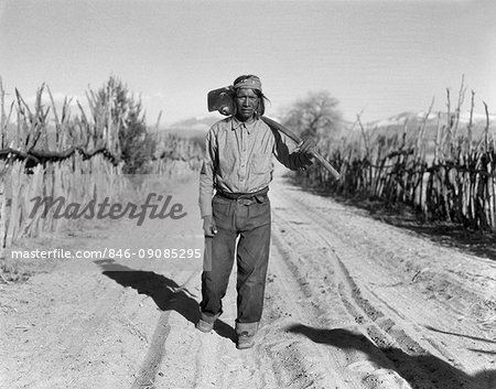 1930s NATIVE AMERICAN INDIAN MAN FARMER WALKING ROAD CARRYING FARM TOOL HOE SAN ILDEFONSO PUEBLO NEW MEXICO USA