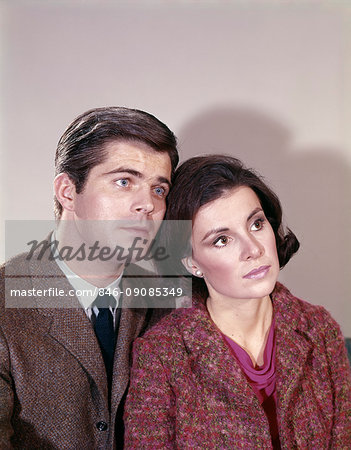 1970s COUPLE MAN BROWN TWEED JACKET HEAD TO HEAD WITH BRUNETTE WOMAN WEAR PINK & GRAY WOOL TOP LOOKING OFF TO SIDE SERIOUS