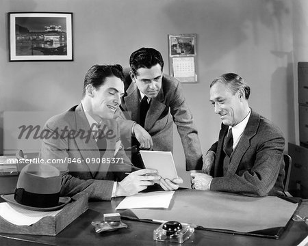 1940s THREE MEN AT OFFICE DESK LOOKING AT PAPERS TABLET MEETING