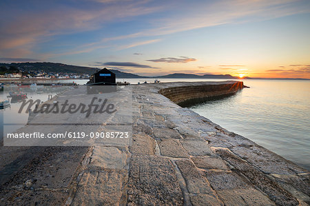 The Cobb with the cliffs of Jurassic Coast at sunrise, Lyme Regis, Dorset, England, United Kingdom, Europe