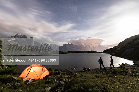 Hikers and tent on the shore of Lacs De Cheserys at night with Mont Blanc massif in the background, Chamonix, Haute Savoie, French Alps, France, Europe