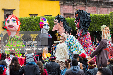 Mojigangas, giant puppets, and crowds of people on the street at the St Michael Archangel Festival procession in San Miguel de Allende, Mexico