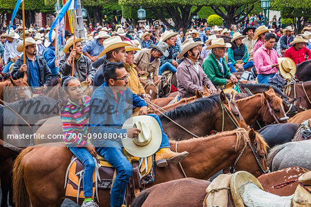 Crowd of horesback riders parading to the Parroquia de San Miguel Arcangel at the St Michael Archangel Festival in San Miguel de Allende, Mexico