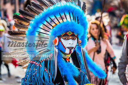 Portrait of male, indigenous tribal dancer wearing blue feathered headdress and looking at the camera in the St Michael Archangel Festival parade in San Miguel de Allende, Mexico