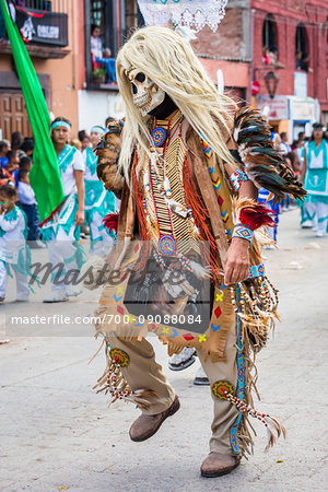 Close-up of an indigenous tribal dancer wearing costume with a skull mask and blond wig in the St Michael Archangel Festival parade in San Miguel de Allende, Mexico