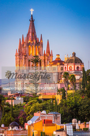 The intircate towers of the Parroquia de San Miguel Arcangel with the cross illuminated at dusk, overlooking the El Jardin in San Miguel de Allende, Mexico