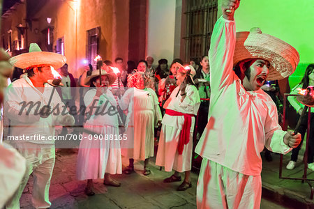 Group of people wearing traditional clothes in street parade at night, re-enacting the peasant uprising for Mexico's Independence Day celebrations in San Miguel de Allende, Mexico