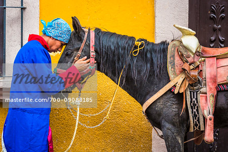 Man in traditional clothing hugging horse's head during historic horseback parade celebrating Mexican Independence Day in San Miguel de Allende, Mexico