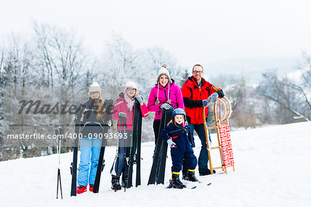 Family in winter vacation doing sport outdoors with sleds and ski