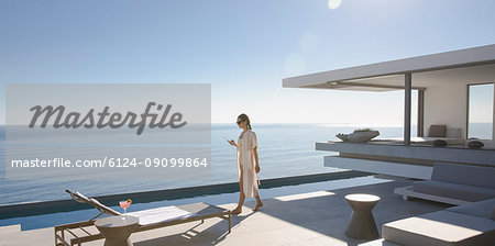 Woman walking on sunny, modern, luxury home showcase exterior patio with ocean view Woman walking on sunny, modern, luxury home showcase exterior patio with ocean view