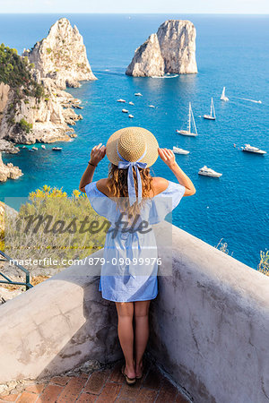 Capri, Naples, Campania, Italy. The cliffs of Capri seen from Belvedere cannone. A girl admiring the view