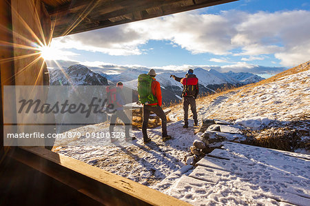 Hikers admiring sunrise from an alpine hut. Livigno, Valtellina, Italy