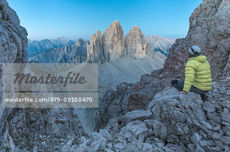 Hiker on the top of mount Paterno / Paternkofel looking the sunrise towards Tre Cime di Lavaredo, Sexten Dolomites, South Tyrol, Bolzano, Italy