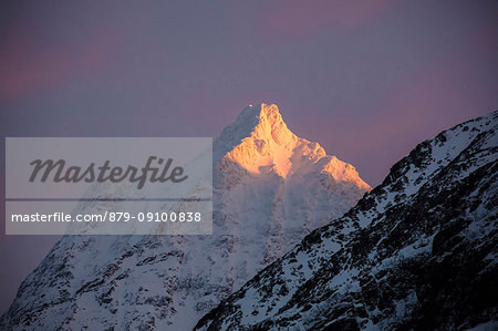 The pink light of sunrise illuminates the snowy peaks of the rocky mountains Svensby Lyngen Alps Tromsø Norway Europe