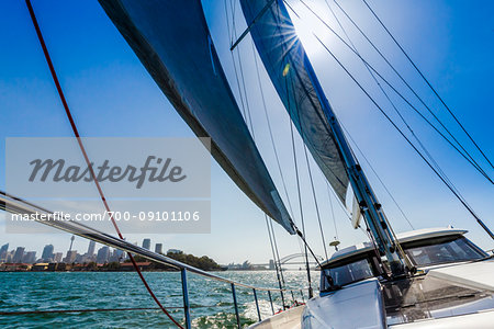 Backlit sails of sailboat in the Sydney Harbour with the CBD and Sydney Harbour Bridge in the background in Sydney, New South Wales, Australia