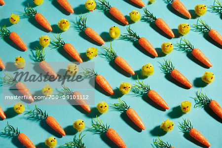 Repetitive carrots and chicken toys setup in rows on a turquoise background Repetitive carrots and chicken toys setup in rows on a turquoise background