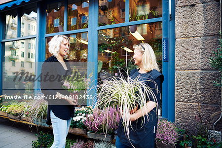 Two florists talking while holding potted plant