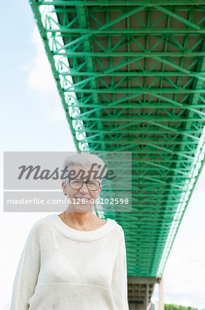 Portrait of senior woman standing under green bridge