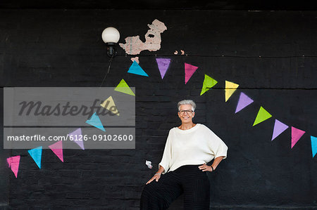 Portrait of senior woman standing against wall
